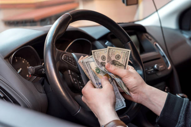 Hands counting cash inside car representing auto insurance savings