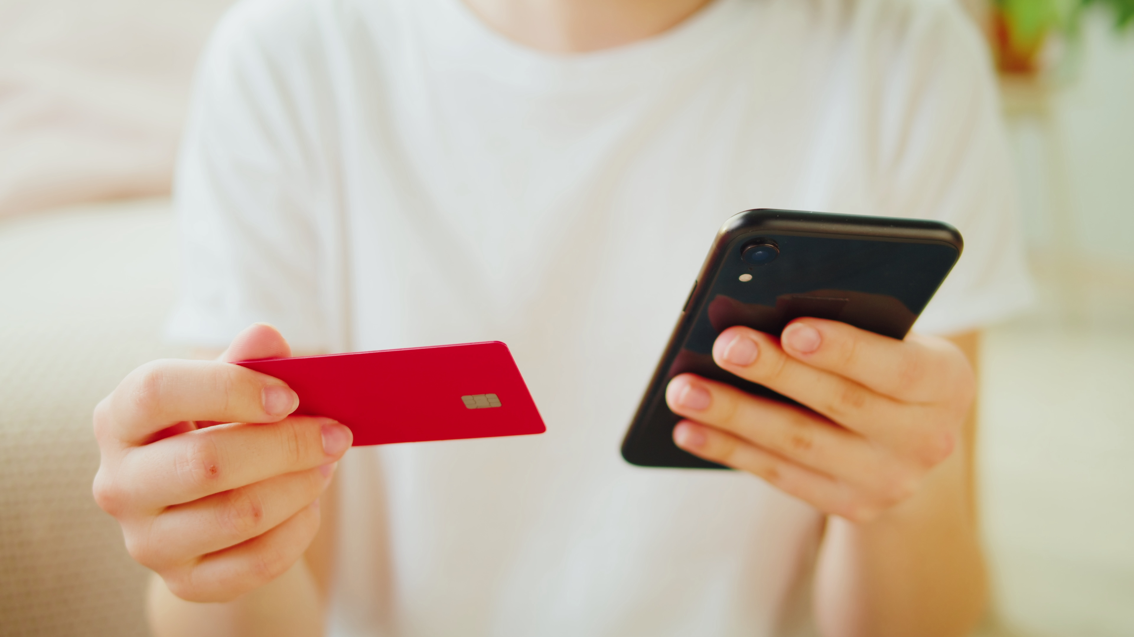 Person holding red credit card and smartphone for mobile shopping and payments